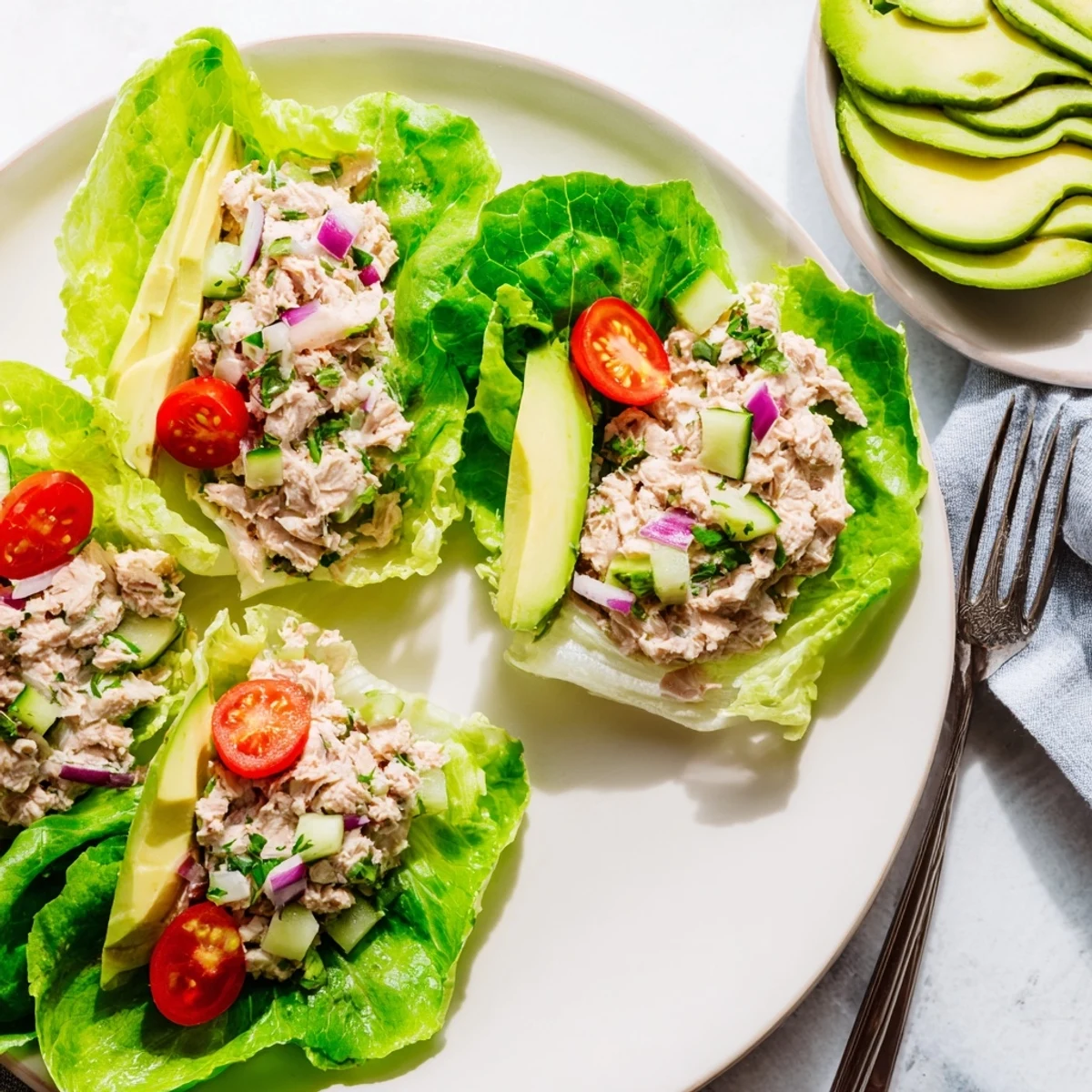 Fresh tuna salad wrapped in crisp butter lettuce leaves topped with avocado slices and cherry tomatoes