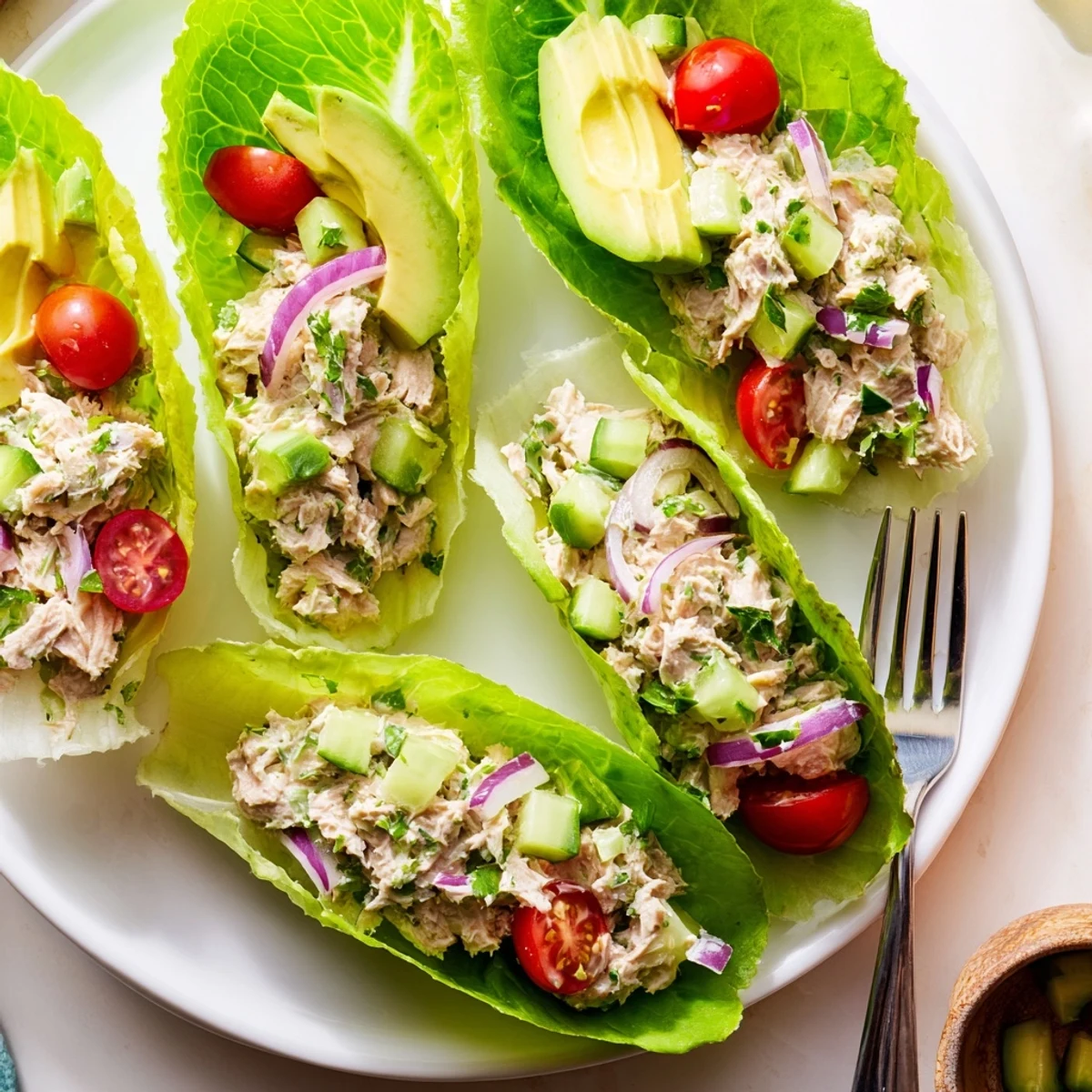 Protein-rich tuna salad spooned into romaine lettuce leaves with fresh parsley and red onion for a low-carb lunch