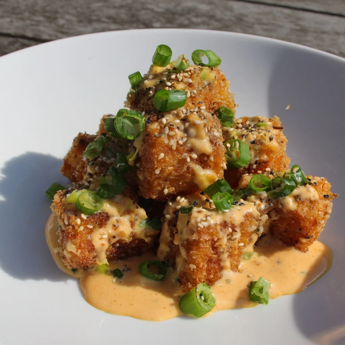 Crispy salmon bites drizzled with spicy Bang Bang sauce served as appetizer or main