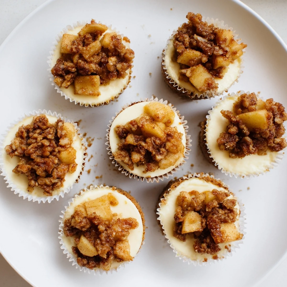 Creamy apple crisp mini cheesecakes with golden oat crumble topping on graham cracker crust