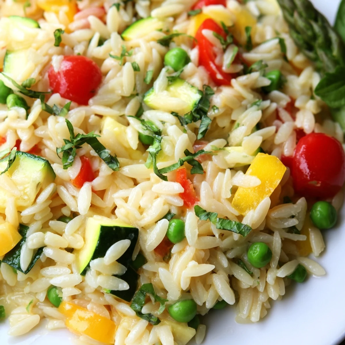 Creamy Orzo Primavera tossed with colorful spring vegetables and fresh herbs in skillet