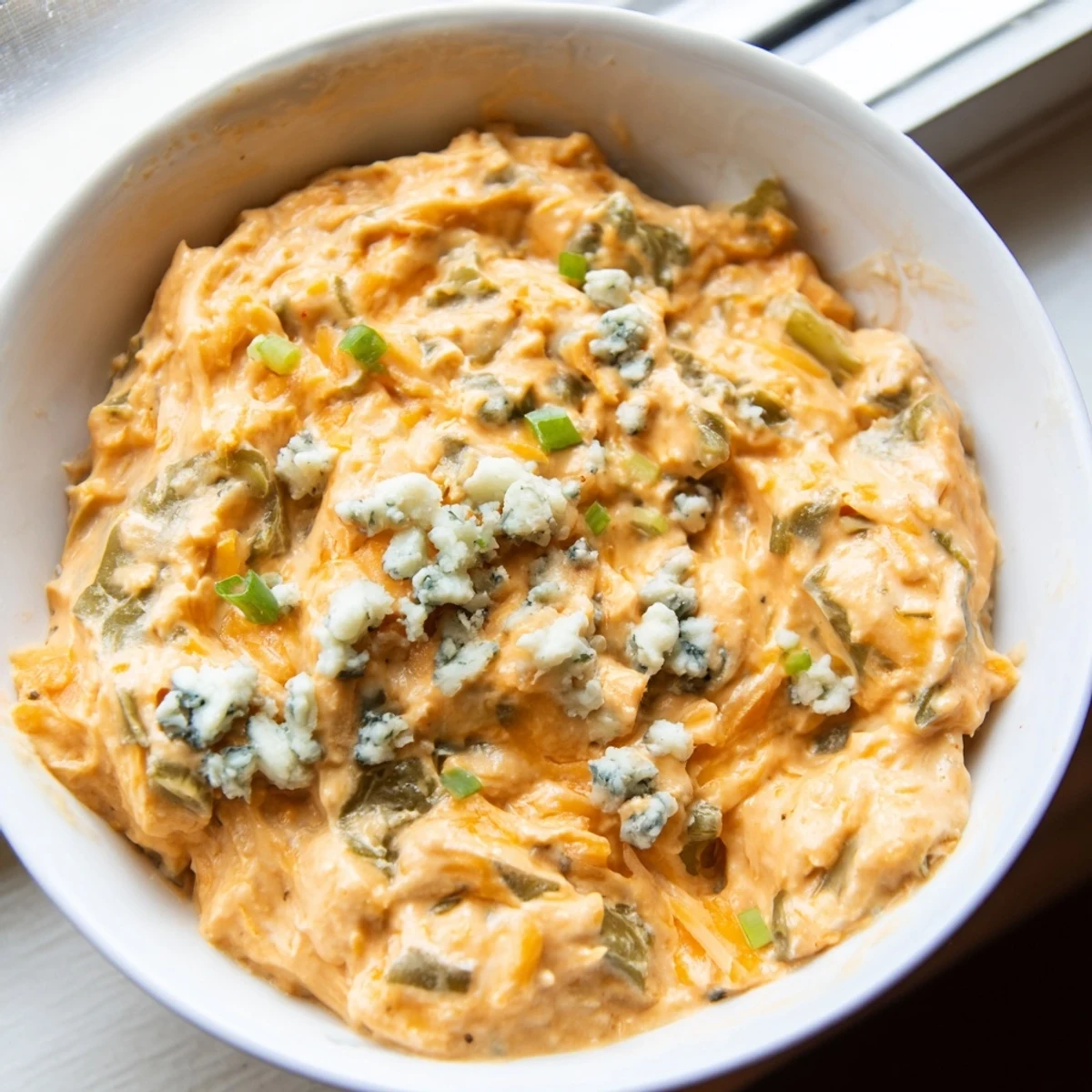Tangy buffalo pickle dip topped with fresh chives and pickle slices on a rustic platter