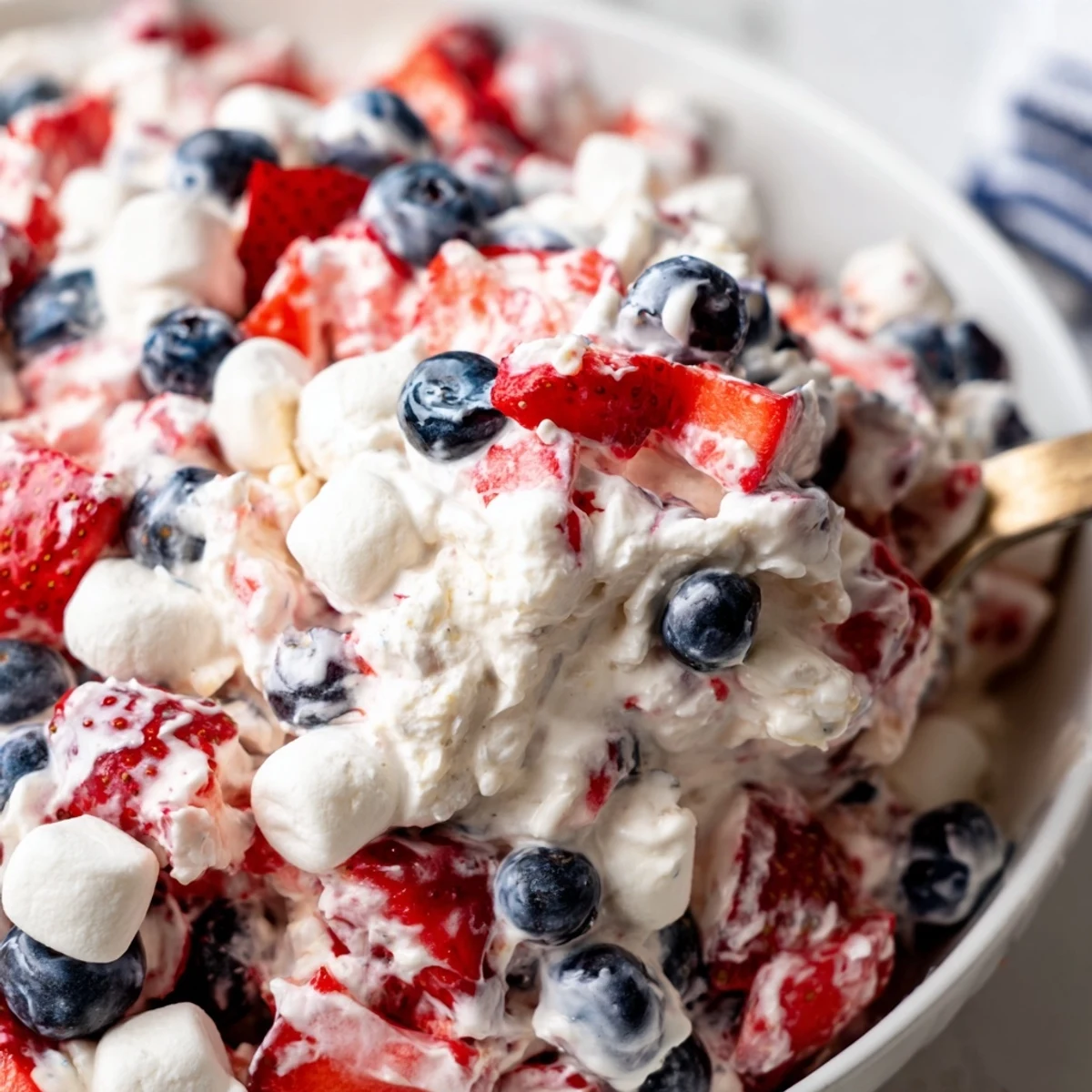 Creamy red white blue cheesecake salad topped with fresh strawberries and blueberries