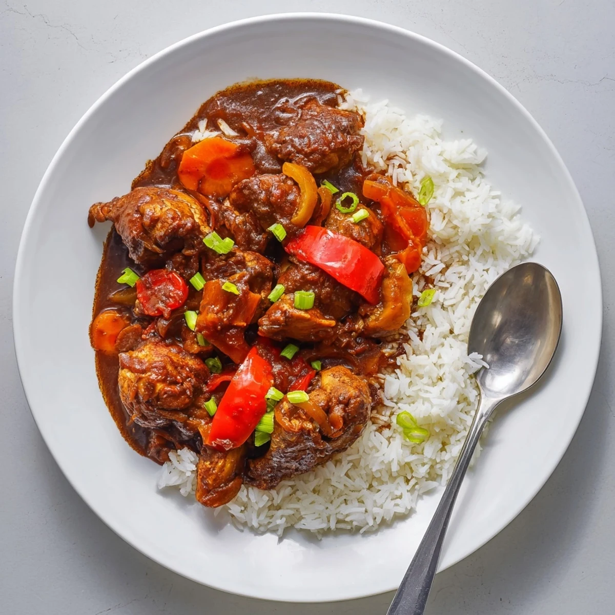 Juicy Jamaican brown stew chicken nestled in a deep reddish-brown stew with tender vegetables and fresh thyme sprigs