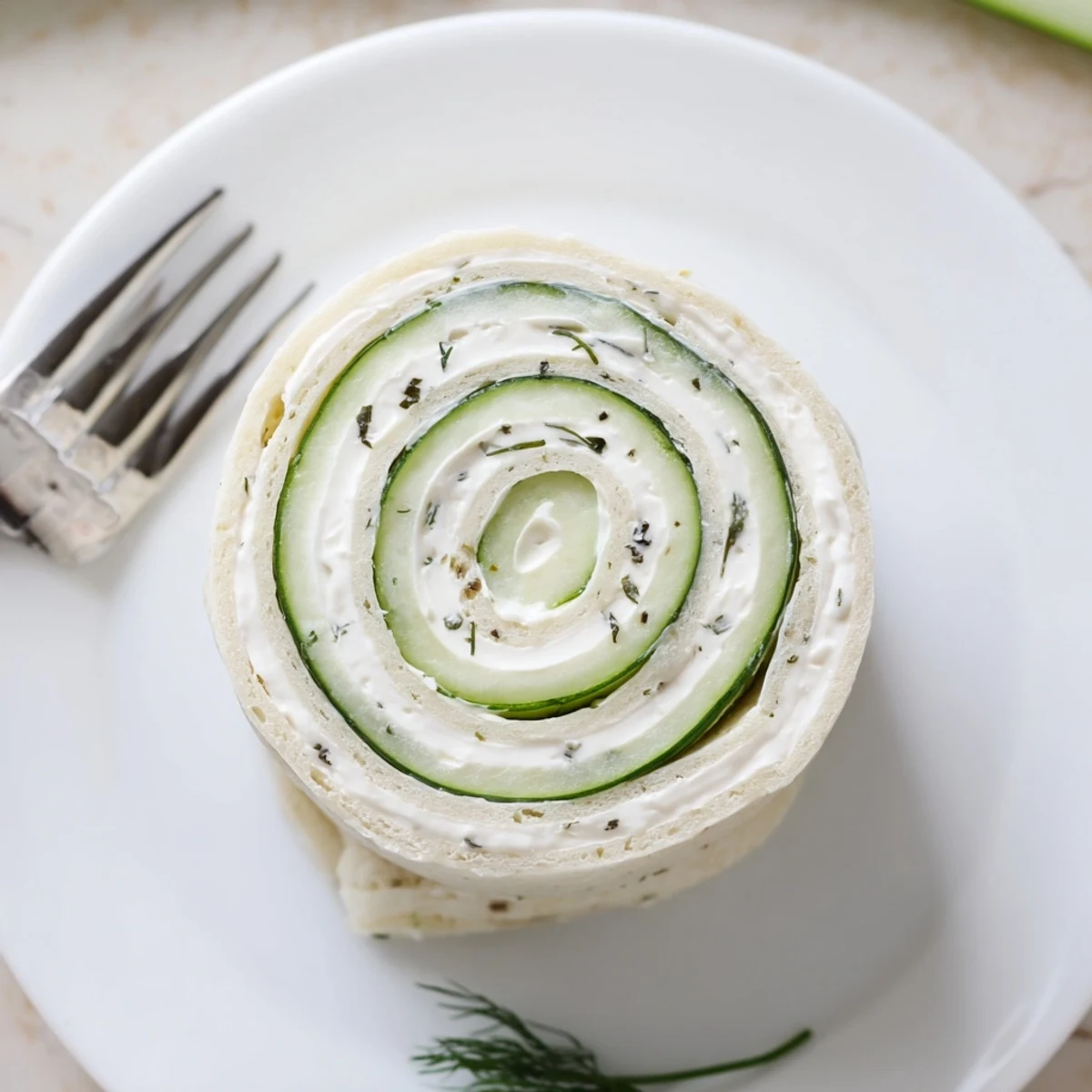 Soft tortilla Cucumber And Dill Pinwheels rolled tight, chilled, garnished with fresh dill