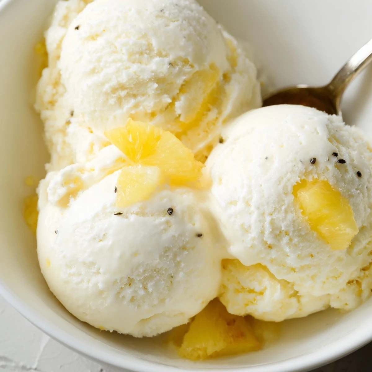 Creamy Pineapple Ice Cream scoops in a chilled bowl, tropical aroma.
