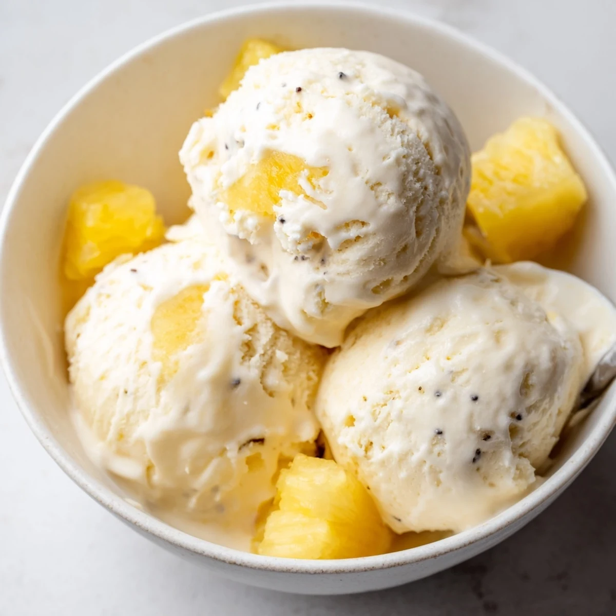 Creamy Pineapple Ice Cream topped with toasted coconut and rum drizzle.
