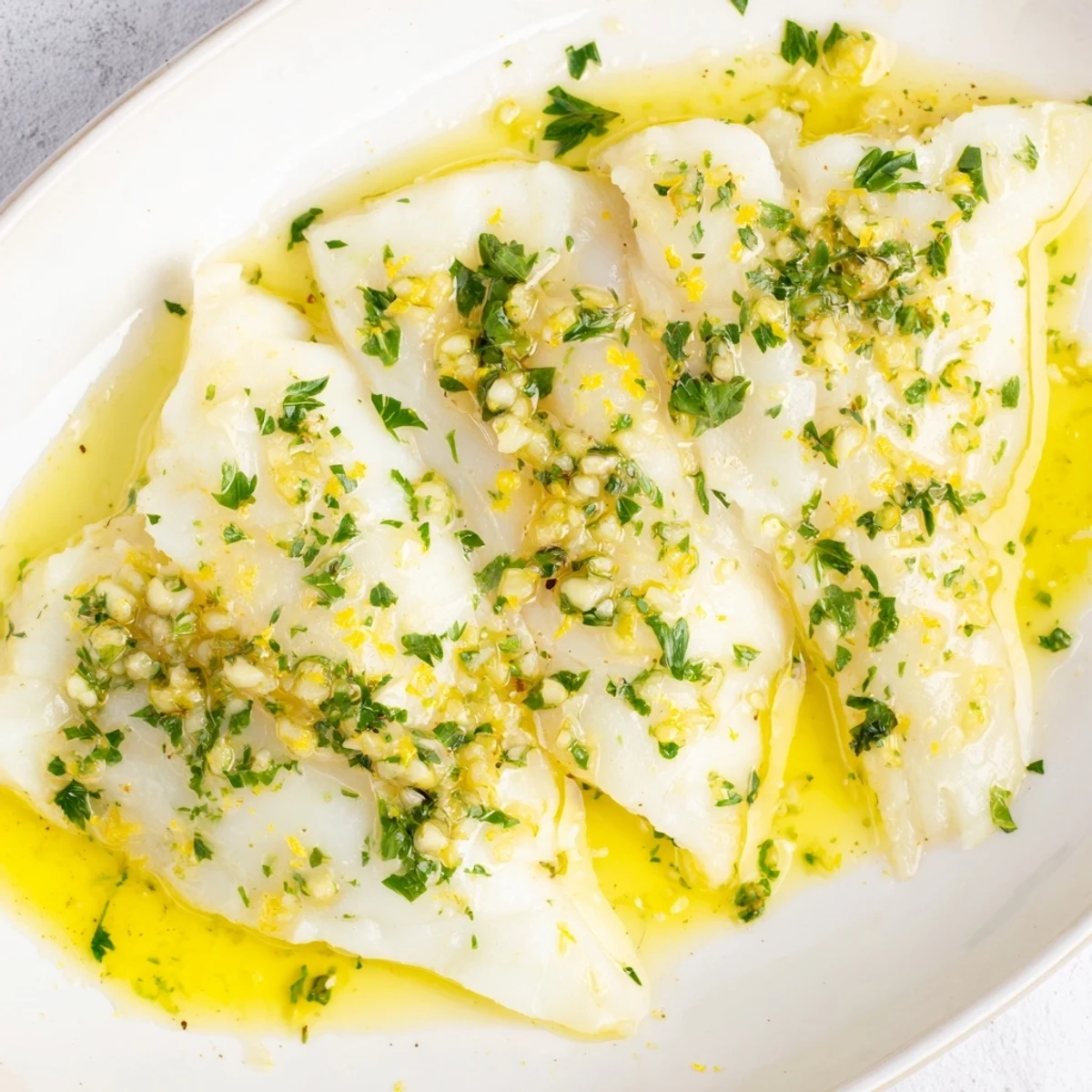 Tender lemon garlic butter cod pieces topped with chopped parsley and zest garnish