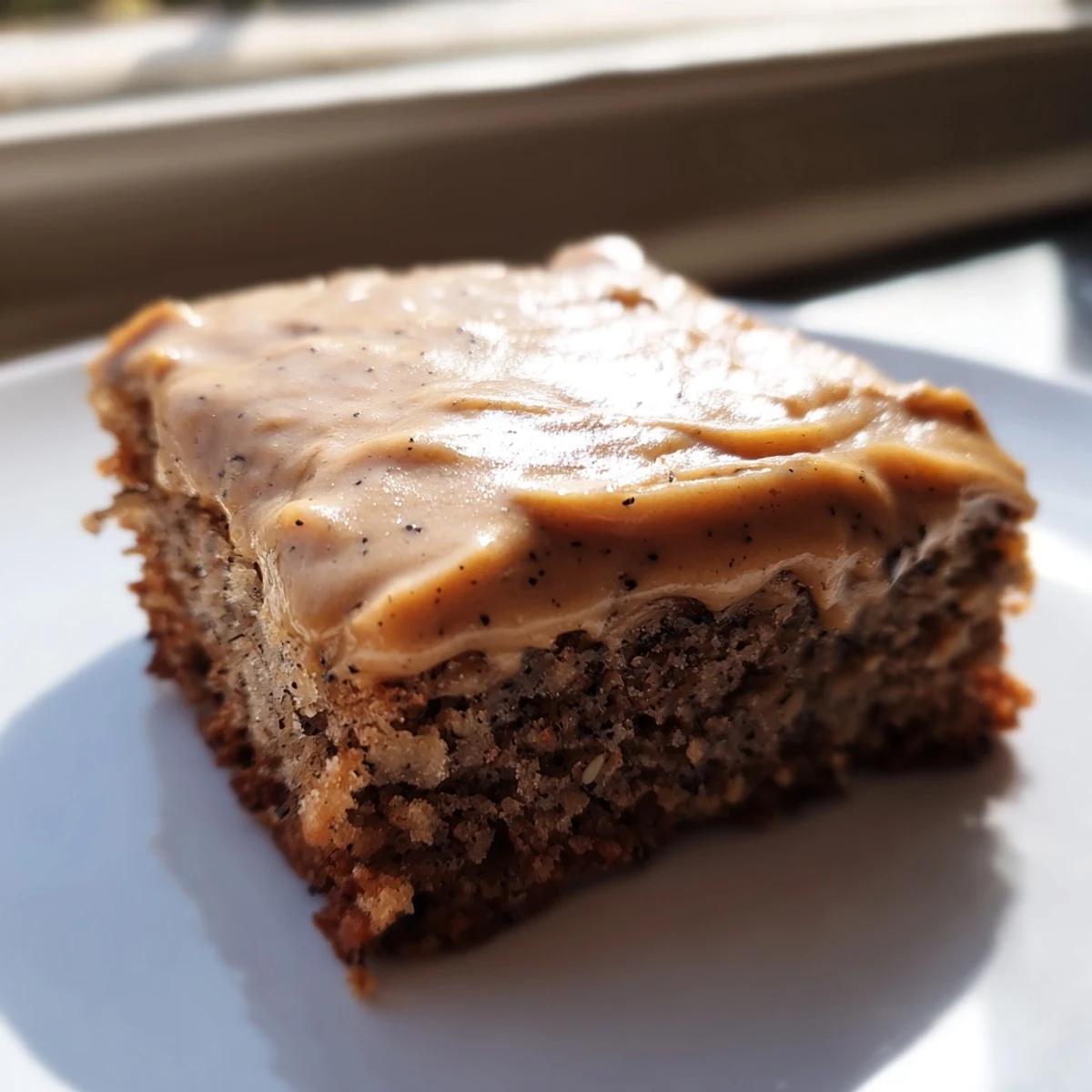 Moist banana bread brownies topped with creamy brown butter frosting on a white plate