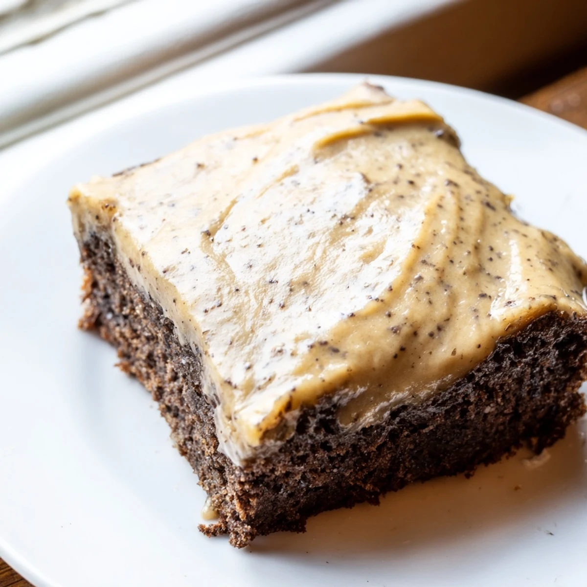 Square slice of banana bread brownie with thick brown butter frosting on serving platter