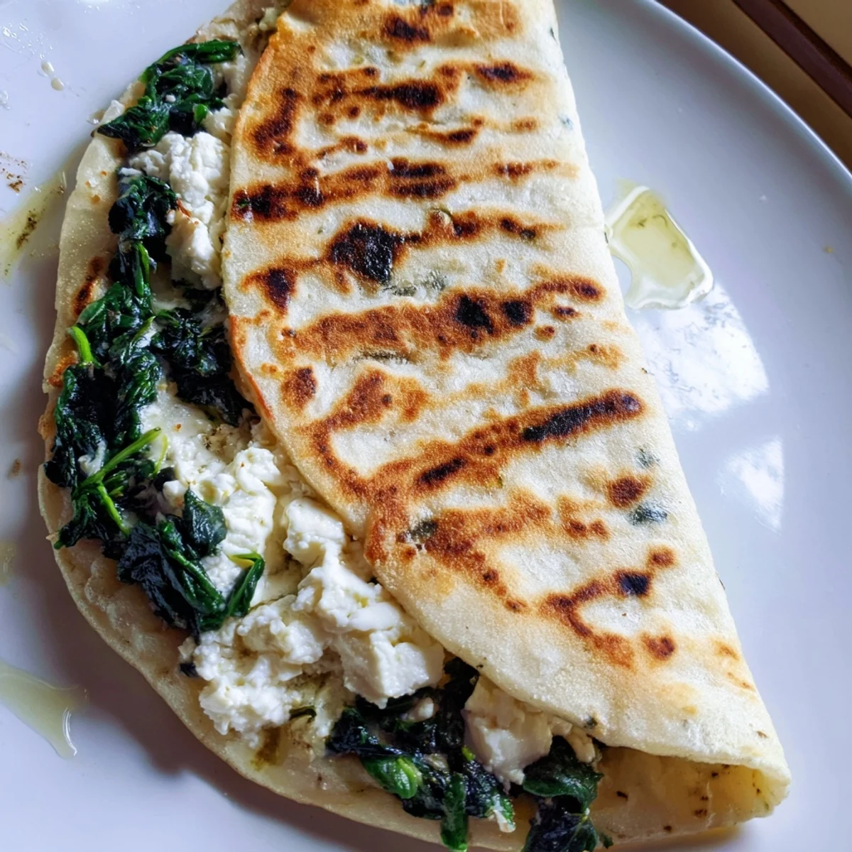 Homemade spinach feta gozleme flatbread sliced into wedges on a wooden serving board