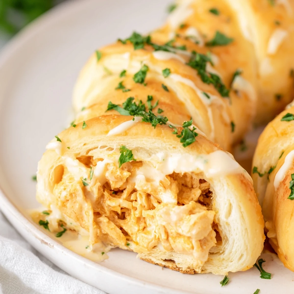 Golden baked chicken pillows with creamy parmesan sauce drizzled over flaky crescent dough