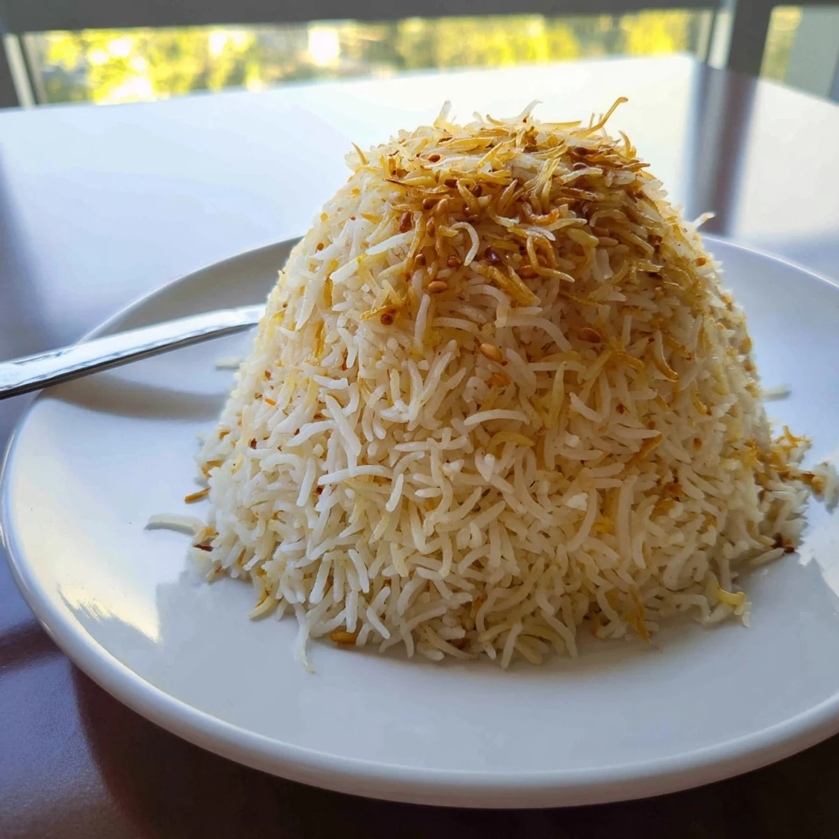Buttery Lebanese rice pilaf studded with crispy browned noodles on a ceramic plate
