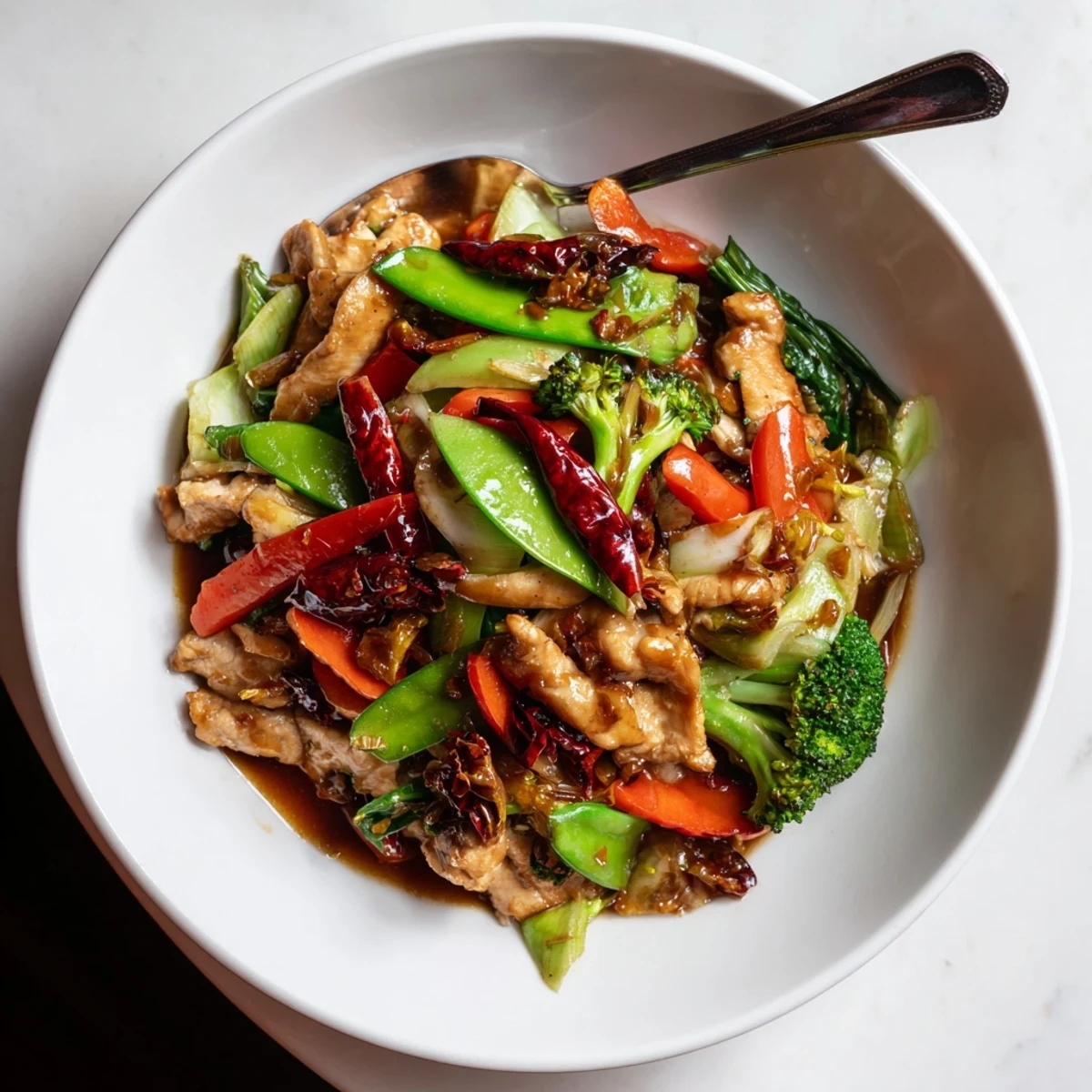Sizzling Hunan Chicken with vibrant bell peppers and broccoli in a spicy garlic sauce