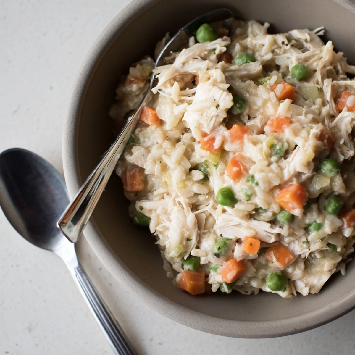 Creamy chicken pot pie orzo in a white bowl garnished with fresh parsley.
